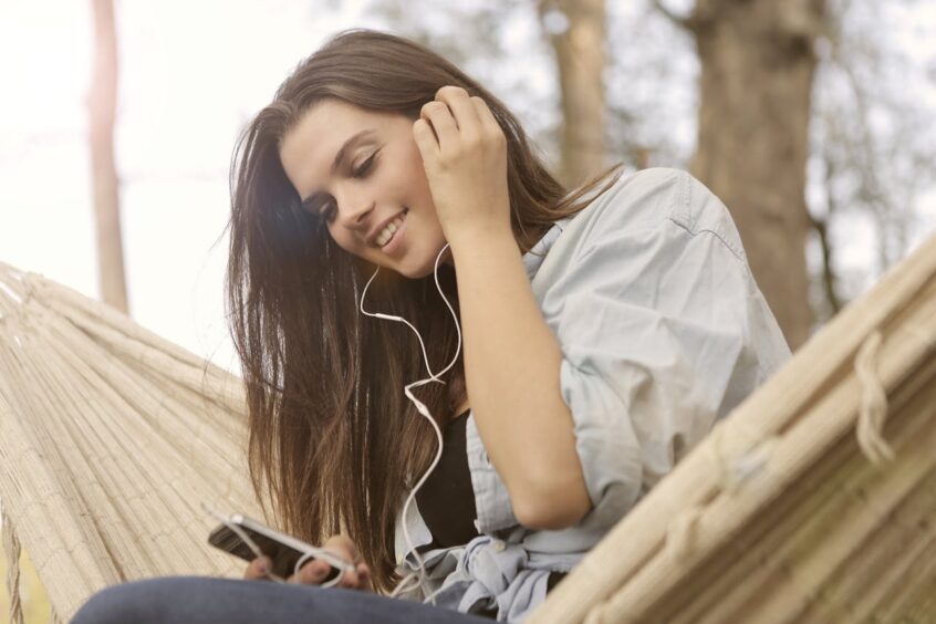 Girl wearing earbuds on hammock